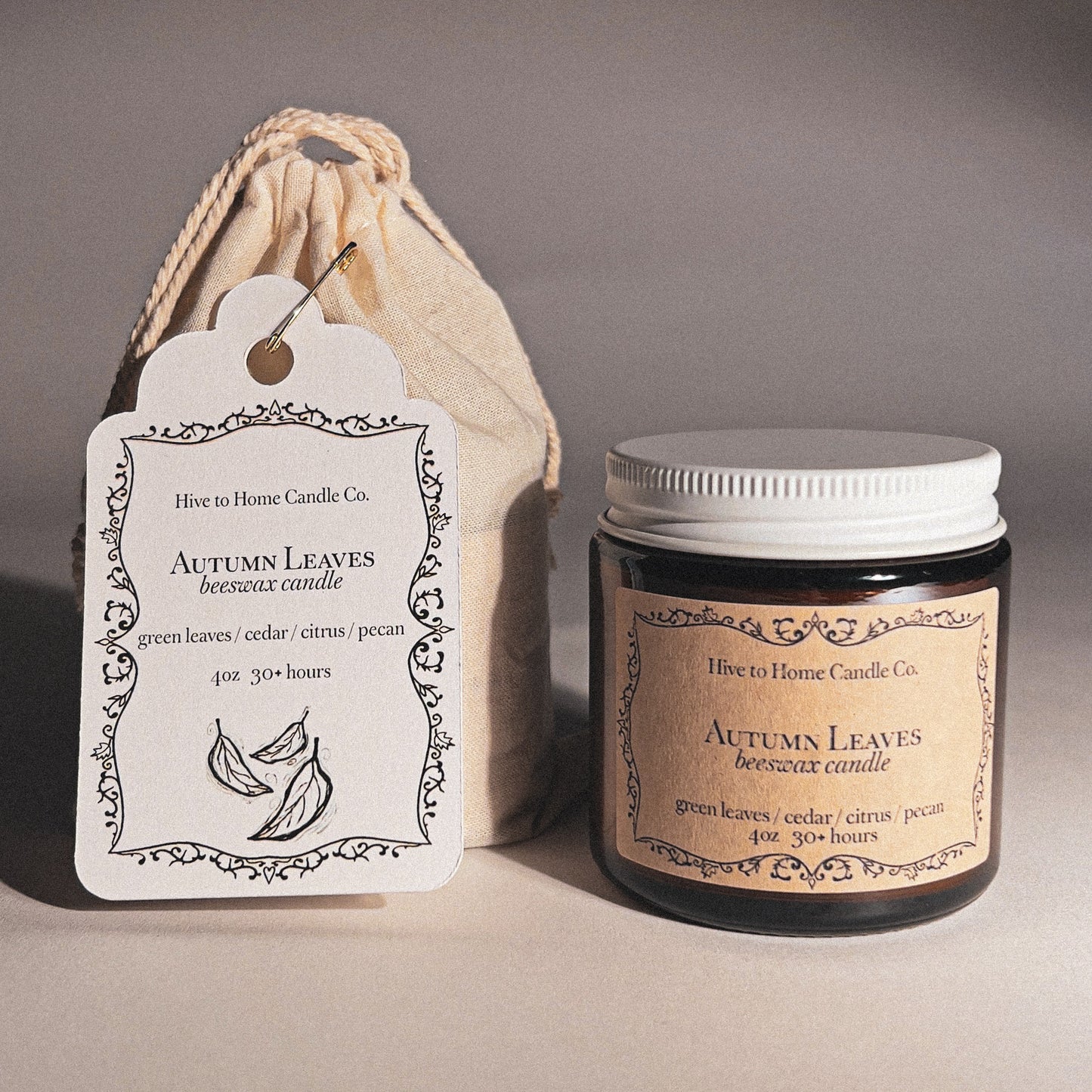 Beeswax candle labeled 'Autumn Leaves' with a matching label and drawstring bag on a neutral background.