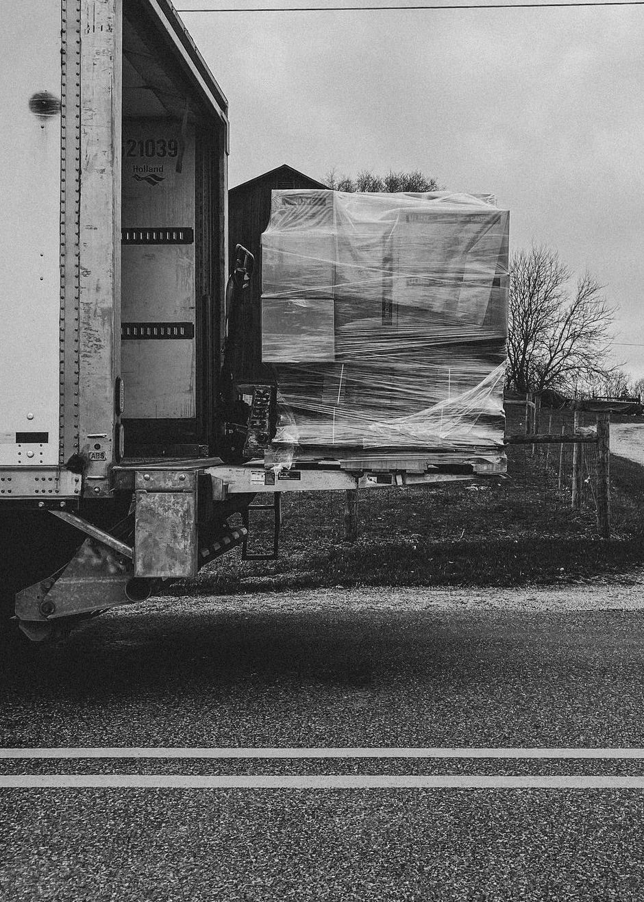 Truck with a large box wrapped in plastic on a road. Candle supplies freight shipment