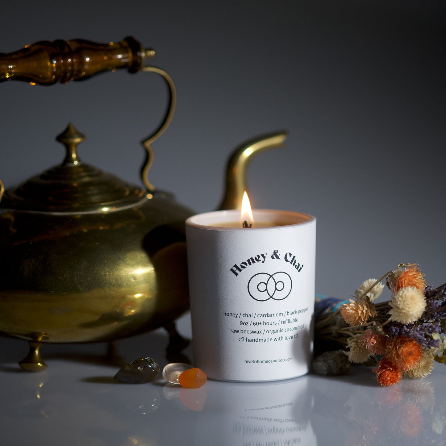 Burning candle image with decorative background. Honey & chai scented beeswax candle. 9 oz white tumbler candle.