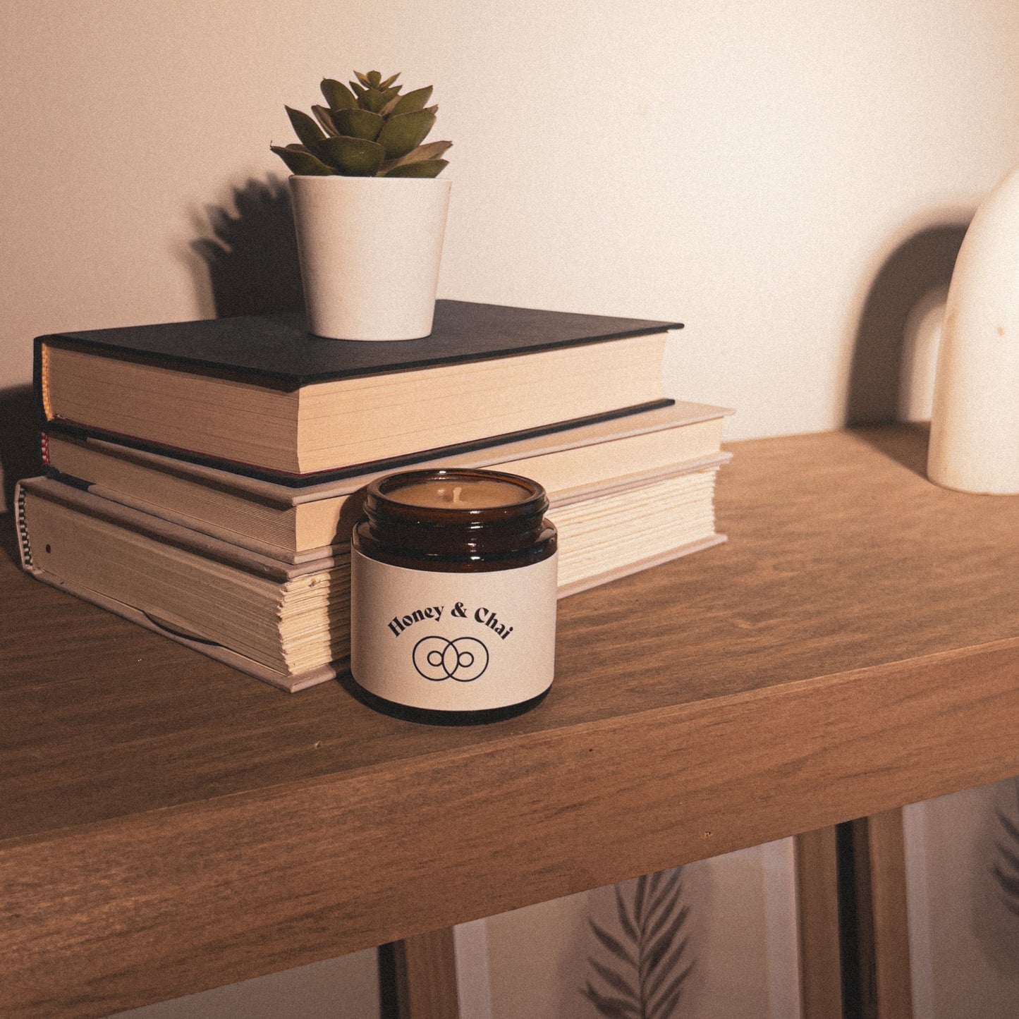 Honey & Chai Cute Size 4 oz Candle, Warm lighting on candle and books on a shelf, aesthetic home decor.