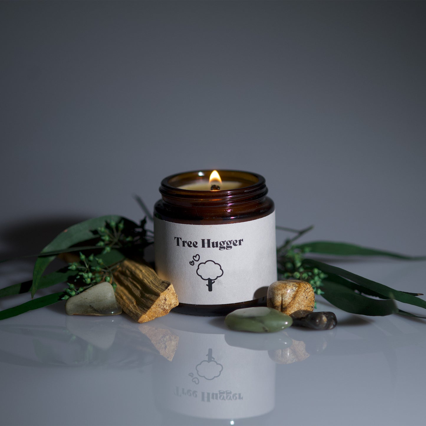 burning candle, lit flame. Tree Hugger cute candle. Pine and cedar candle