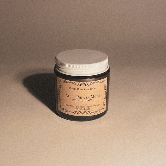 4 oz Apple Pie scented candle in an amber jar with a white lid and decorative beige label. 