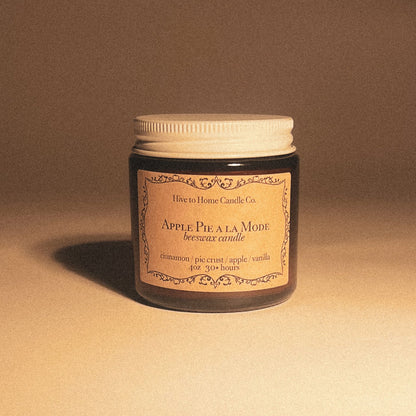 4 oz fall scented candle smells like baked apple pie with a brown label in amber glass jar with white lid.