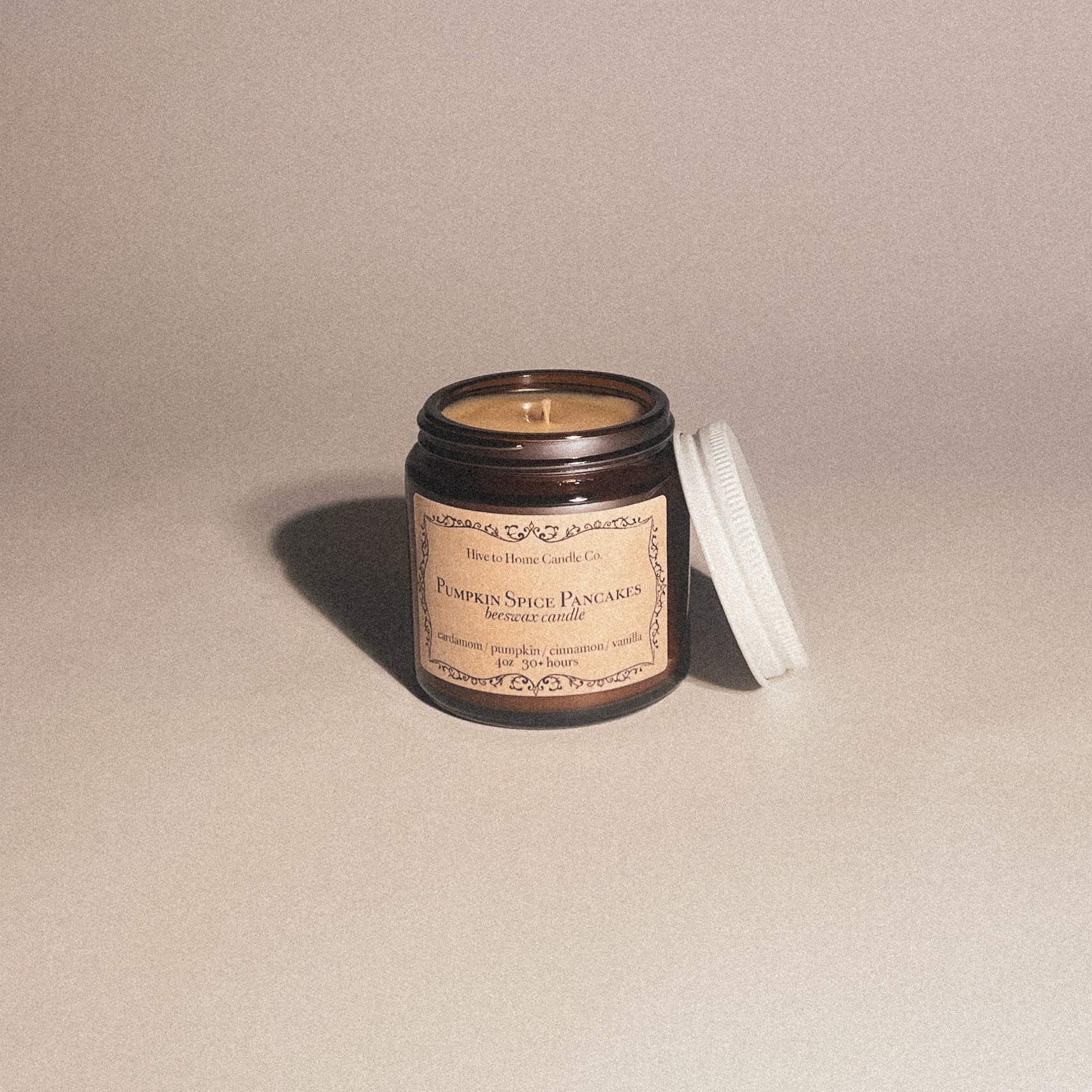 4 oz pumpkin spice pancake fall scented candle with white lid leaning on amber jar.